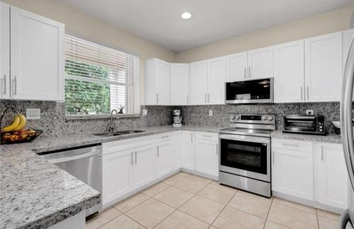 a kitchen with white cabinets and a stove top oven at Aloha in Homestead