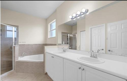 a bathroom with two sinks and a tub and a mirror at Aloha in Homestead