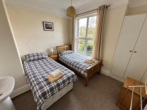 two beds in a room with a sink and a window at 21 Trinity Avenue in Llandudno