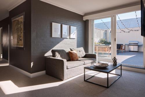 a living room with a couch and a table at Harbour Rocks by Ode Hotels in Sydney