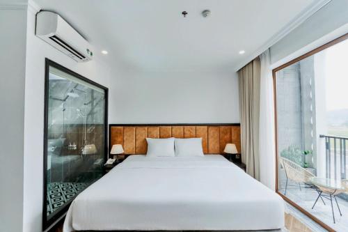 a bedroom with a bed and a large window at Eden Hotel Cát Bà in Cat Ba
