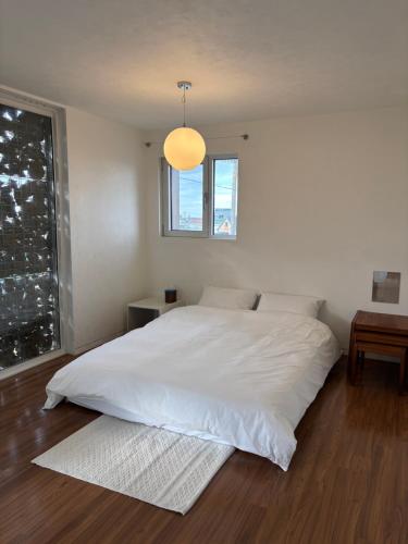 a bedroom with a large white bed and a window at Kimnung House Anmok in Jeju