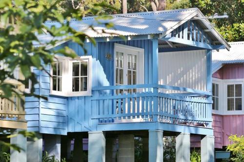 a blue house with a porch and a balcony at Cottage 5 Hyams Beach Seaside Cottages in Hyams Beach