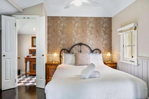 a bedroom with a white bed with a floral wallpaper at Cottage 5 Hyams Beach Seaside Cottages in Hyams Beach