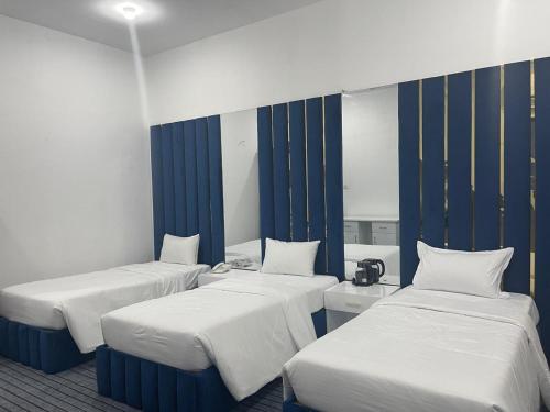 three beds in a room with blue and white stripes at The Beach Villa in Mount Lavinia