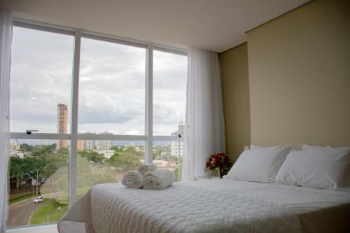 a bedroom with a large window with towels on a bed at Select Hotel in Palmas