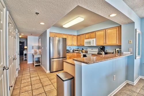 a kitchen with wooden cabinets and a stainless steel refrigerator at Oceanfront Crescent Shores Unit 106-Sleep12-4 bedrooms-6 beds-3 bathrooms in North Myrtle Beach