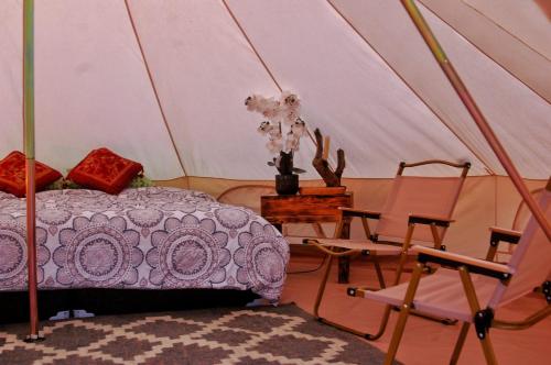 a bedroom with a bed and chairs in a tent at Chantli Nawi in Ixtafiayuca