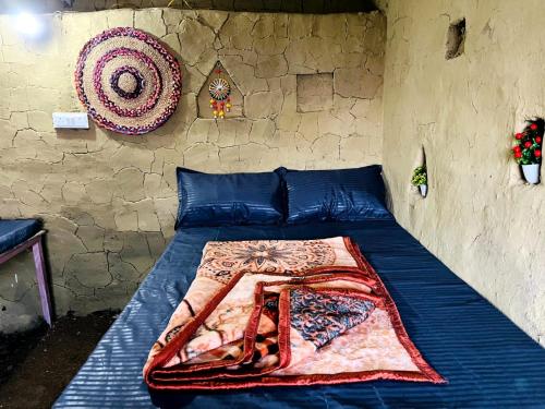 a bed with a blanket on it in a room at Thatharana Trek by Mountain Hikers - Mudhouse & Cafe in Dharmsāla