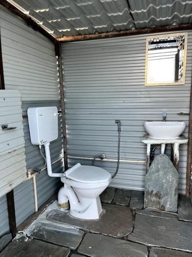 a bathroom with a toilet and a sink at Thatharana Trek by Mountain Hikers - Mudhouse & Cafe in Dharmsāla