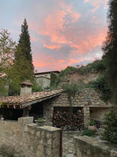 a stone building with a stone wall and a tree at La Casa de Los Moyas in Olba