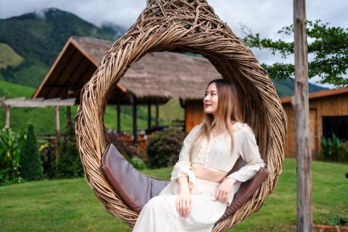 a woman is sitting in a wicker chair at กระซิบหมอกแอทสะปัน in Ban Nong Chaeng