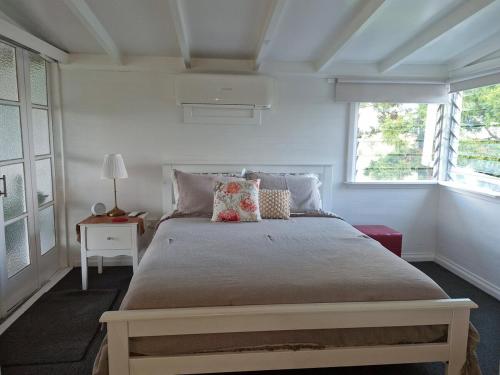 a bedroom with a large bed and two windows at Cottage on the Burnett, Mundubbera in Mundubbera