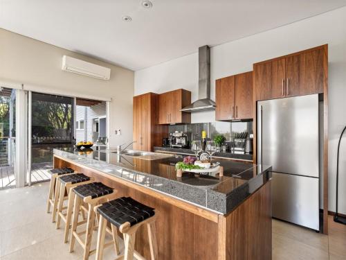 a kitchen with a stainless steel refrigerator and wooden cabinets at A La Plage - Ocean View Luxury - Family Friendly in Gnarabup