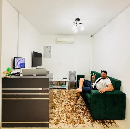 a man sitting on a couch in a living room at Muscat Dormitory Male&Female in Muscat