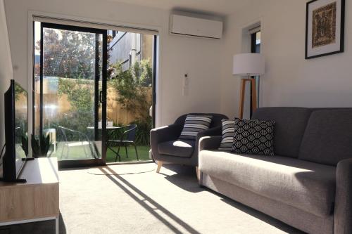 a living room with a couch and a sliding glass door at Modern CBD, Walk to Te Pae, Across from Casino, FREE Parking in Christchurch
