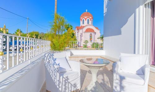 a balcony with two chairs and a table and a building at Archontariki Luxury suites collection in Lakithra village in Lakithra