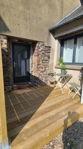 a wooden deck with two chairs and a table at Maison de bourg bretonne in Baulon