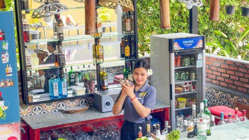 a woman standing in front of a bar taking a picture at Villa Indochine d'Angkor in Siem Reap
