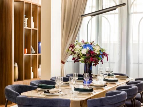 une longue table avec des chaises bleues et un vase de fleurs dans l'établissement Merveil - Signature Suite -Tour Eiffel- Grenelle I, à Paris