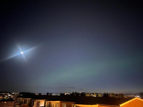 a bright light in the sky over a city at night at Cosy room in a family flat in Oslo