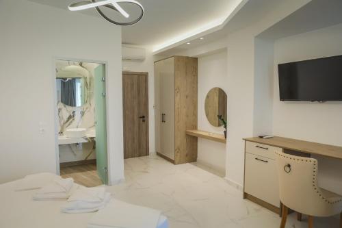 a bathroom with a vanity and a tv on a wall at Theo Beach Hotel Apartments in Rethymno Town