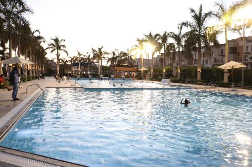 a pool at a resort with people swimming in it at Luxury Stylish Modern 2 Beds Hotel Apartment - East Town Compound - Sodic -New Cairo - Cairo - Egypt in Cairo
