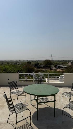 a green table and chairs on a patio at Sheopur Shikaar Oudi in Sheodāspura