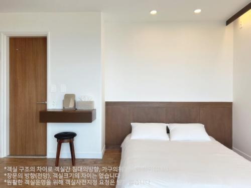 a bedroom with two beds and a stool in it at Gongzone Stay in Jeju