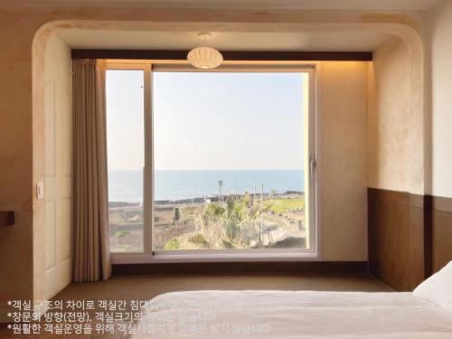 a bedroom with a large window with a view of the ocean at Gongzone Stay in Jeju