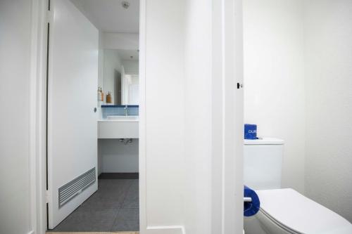 a white bathroom with a toilet and a sink at Little Drifter North Melbourne in Melbourne