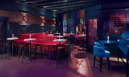 a bar with red tables and stools in a room at Kimpton De Witt Amsterdam by IHG in Amsterdam