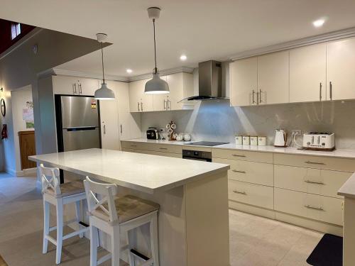 a kitchen with white cabinets and a kitchen island with stools at Eagles Eyrie Spa Lodge in Vacy