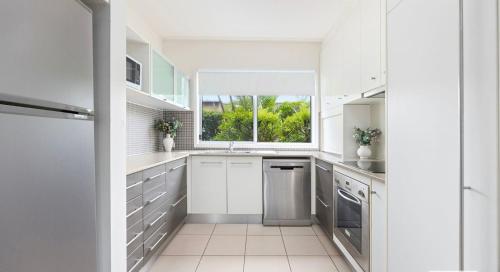 a kitchen with white cabinets and a window at Quarterdecks Retreat in Hervey Bay