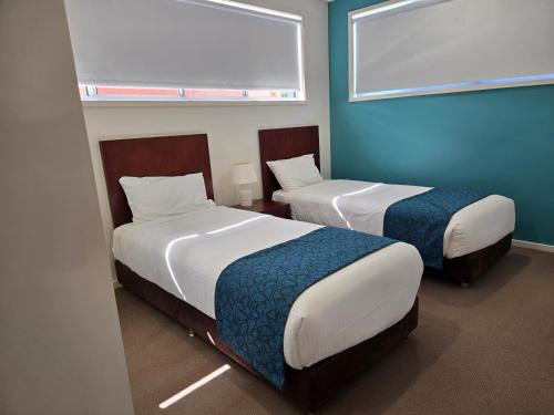 two beds in a room with blue walls at Quarterdecks Retreat in Hervey Bay