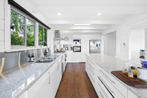 a white kitchen with white cabinets and wooden floors at Nature Comfort Views Dromana Family Retreat in Dromana