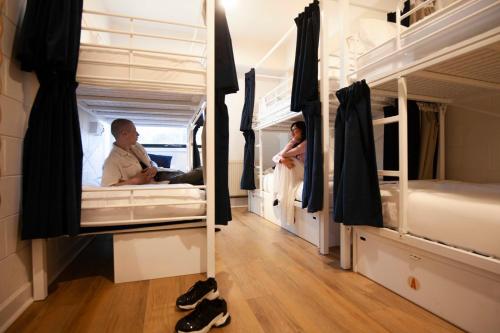 a man and a woman standing in a room with bunk beds at Little Drifter North Melbourne in Melbourne