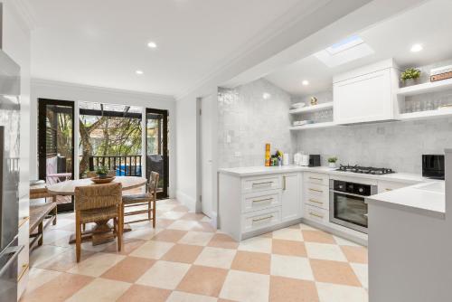 a kitchen with white cabinets and a table with chairs at 5BR Paddington Home w Private Parking and Studio in Sydney