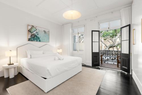 a white bedroom with a white bed and a window at 5BR Paddington Home w Private Parking and Studio in Sydney