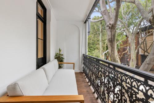 a white couch on a balcony with a window at 5BR Paddington Home w Private Parking and Studio in Sydney