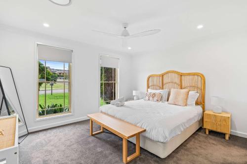 a white bedroom with a large bed and a table at Caves Beach House by Coast Hosting in Caves Beach