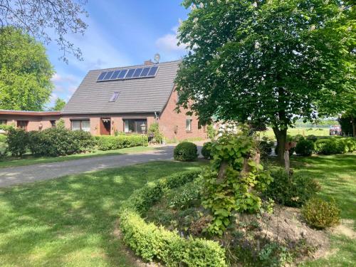 une maison avec un arbre dans la cour dans l'établissement Ferienhaus WALDBLICK by fewo-plan WING142 Nähe Naturpark Wingst, à Armstorf