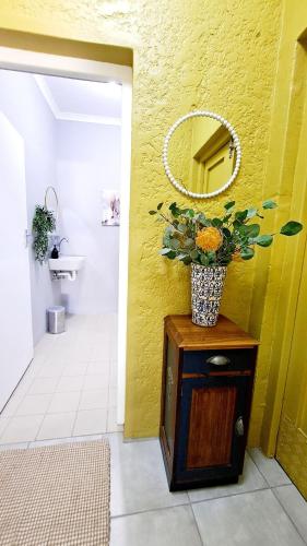 a bathroom with a mirror and a vase of flowers on a cabinet at Happy'Nest at Garden Route in Riversdale