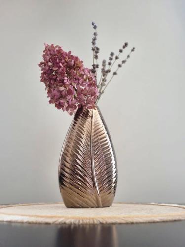 a metal vase with purple flowers in it at Few Steps to the Bay in Jūrmala