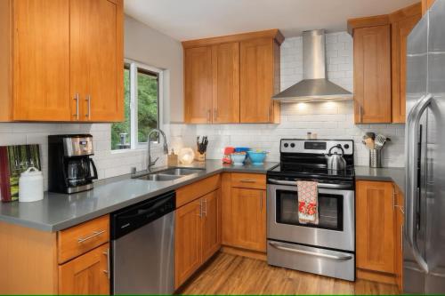 a kitchen with stainless steel appliances and wooden cabinets at Spacious Main Street Retreat for families and large groups in Edmonds