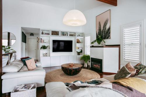 a living room with white furniture and a tv at Jungle Cubby by Coast Hosting in Terrigal