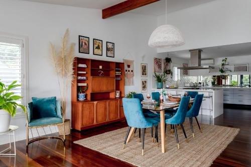 a kitchen and dining room with a table and blue chairs at Jungle Cubby by Coast Hosting in Terrigal
