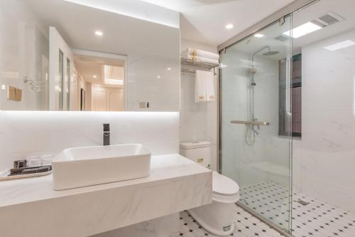 a white bathroom with a sink and a shower at 重庆大野江景民宿 in Chongqing