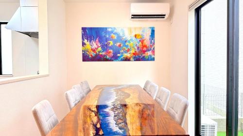 a dining room with a table and a painting on the wall at NIRAI Yofuke in Nago