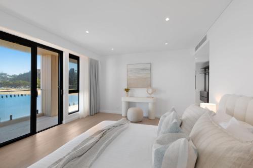 a white living room with a white couch and large windows at Maggie's by Coast Hosting in North Avoca
